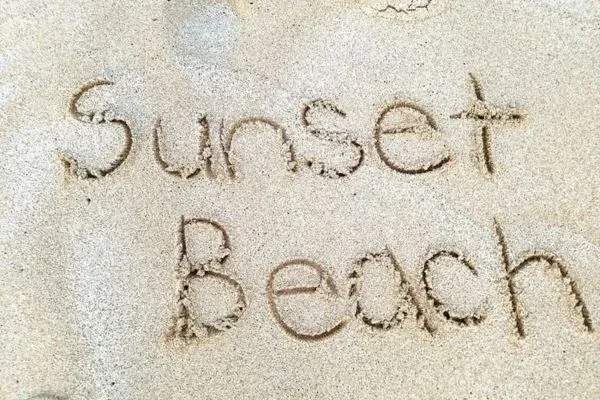 The words 'Sunset Beach' written in the sand at Sunset Beach Park.