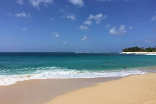 A serene view of the ocean at Sunset Beach Park, with gentle waves and a clear blue sky.